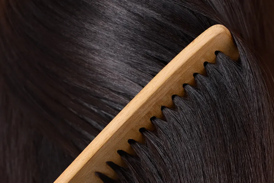 Glänzendes dunkles Haar mit Holzkamm